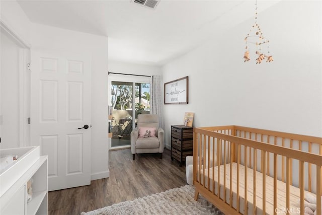 bedroom with wood finished floors, visible vents, and baseboards