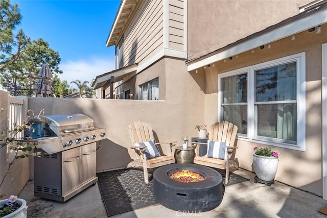 view of patio / terrace featuring a grill, a fire pit, and fence