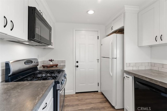 kitchen with white cabinets, gas stove, freestanding refrigerator, and black microwave