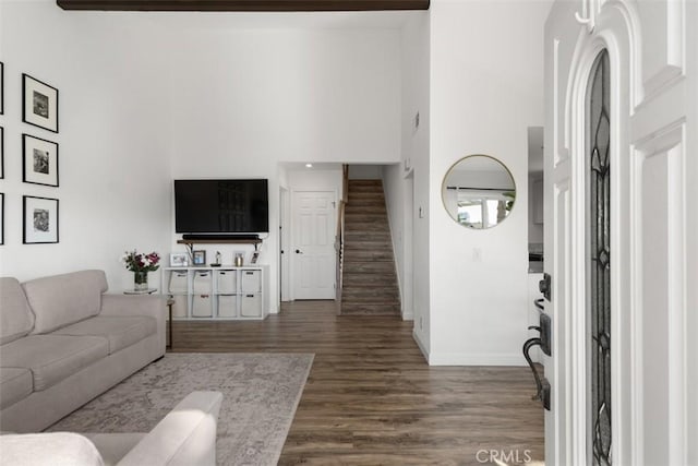 living area featuring dark wood finished floors, stairway, baseboards, and a towering ceiling