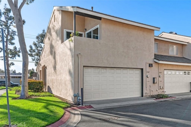 exterior space featuring a garage, a front lawn, and stucco siding