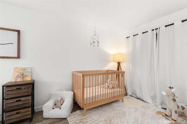 bedroom featuring a nursery area and wood finished floors