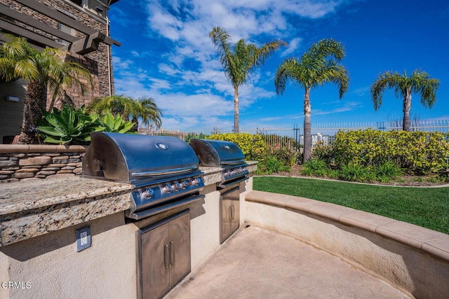 view of patio featuring a fenced backyard, grilling area, and an outdoor kitchen