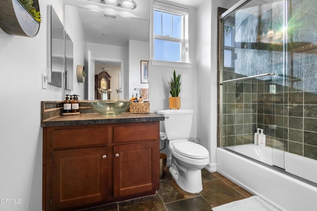 full bath with visible vents, bath / shower combo with glass door, vanity, and toilet