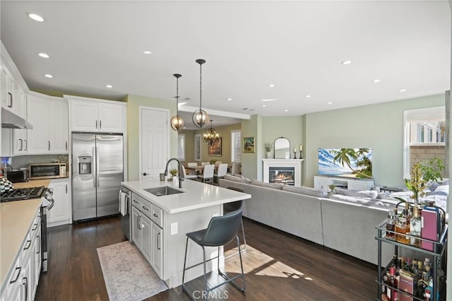 kitchen with dark wood-type flooring, open floor plan, appliances with stainless steel finishes, white cabinetry, and a sink