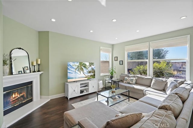 living room featuring a glass covered fireplace, recessed lighting, wood finished floors, and baseboards