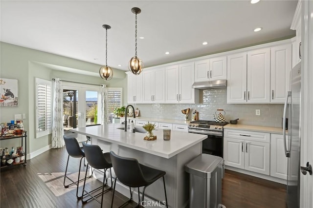 kitchen with tasteful backsplash, under cabinet range hood, light countertops, white cabinets, and stainless steel appliances