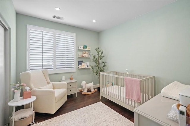 bedroom featuring wood finished floors, visible vents, baseboards, recessed lighting, and a nursery area