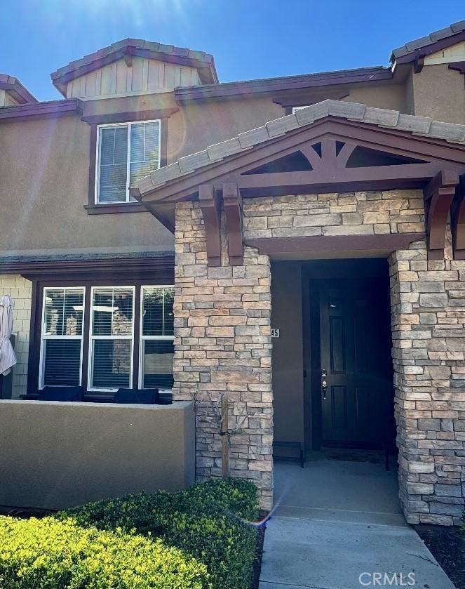 property entrance with stucco siding and stone siding