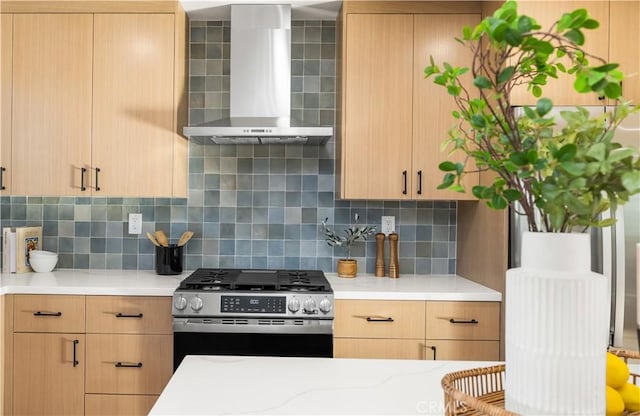 kitchen with gas stove, backsplash, wall chimney exhaust hood, and light brown cabinetry