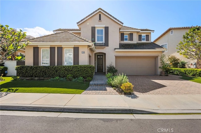 view of front of home with a tile roof, decorative driveway, a garage, and stucco siding