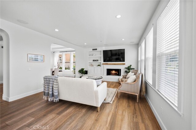 106 Via Sabinas, San Clemente, CA 92673 - living area featuring arched walkways, a lit fireplace, wood finished floors, recessed lighting, and baseboards