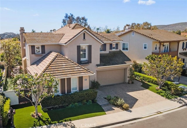 view of front of property with a tile roof, decorative driveway, a garage, and stucco siding