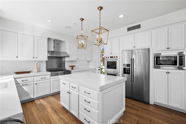106 Via Sabinas, San Clemente, CA 92673 - kitchen featuring appliances with stainless steel finishes, wall chimney range hood, a chandelier, dark wood finished floors, and decorative backsplash