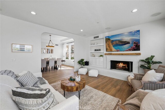 106 Via Sabinas, San Clemente, CA 92673 - living room featuring wood finished floors, recessed lighting, a warm lit fireplace, arched walkways, and built in shelves