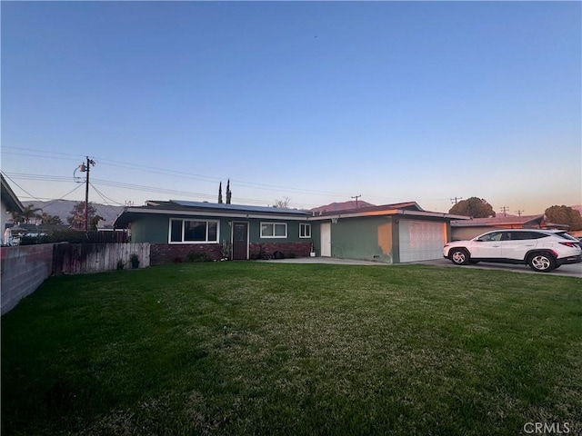 ranch-style home with an attached garage, concrete driveway, a front yard, and fence