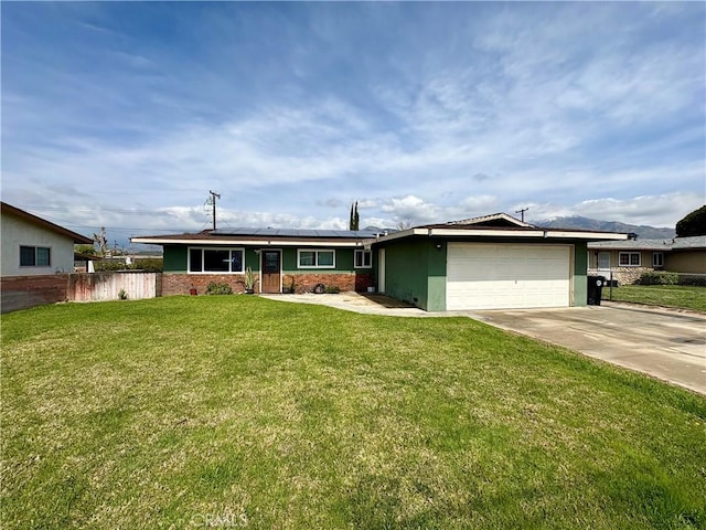 single story home featuring fence, concrete driveway, a front yard, roof mounted solar panels, and an attached garage