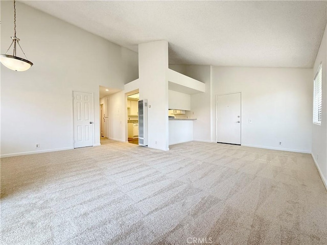 unfurnished living room featuring baseboards, high vaulted ceiling, a textured ceiling, and light colored carpet