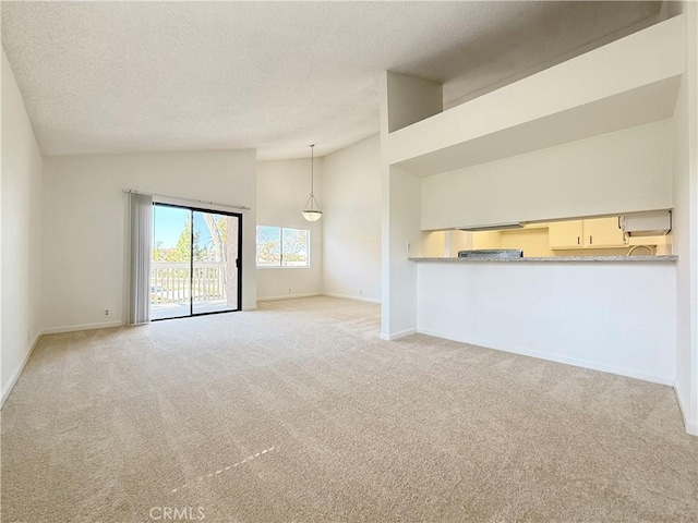 unfurnished living room with high vaulted ceiling, carpet, baseboards, and a textured ceiling