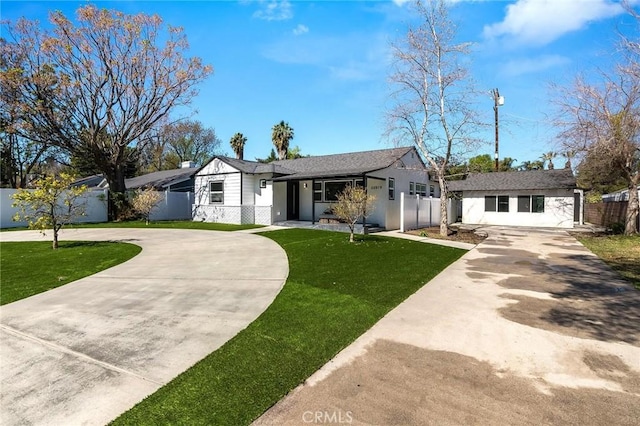 view of front of home with an outdoor structure, concrete driveway, fence, and a front lawn