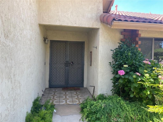 property entrance featuring a tiled roof and stucco siding