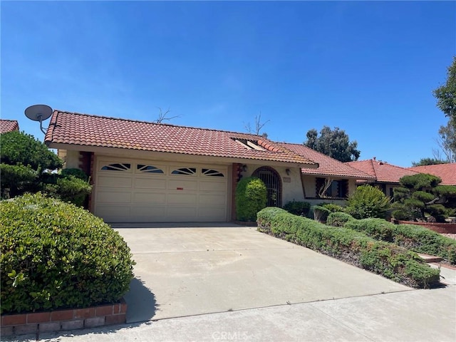 view of front of house featuring concrete driveway, a tiled roof, an attached garage, and stucco siding