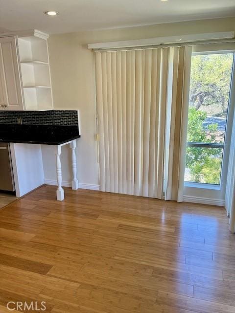 unfurnished living room with recessed lighting, baseboards, and light wood finished floors