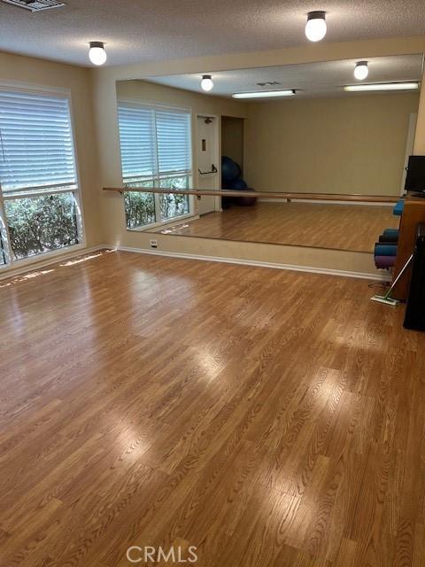 spare room featuring a textured ceiling, wood finished floors, visible vents, and baseboards