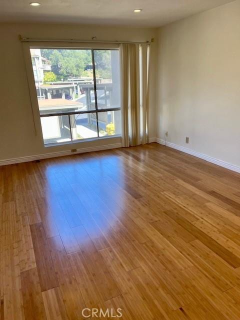 unfurnished room with baseboards, wood finished floors, and recessed lighting