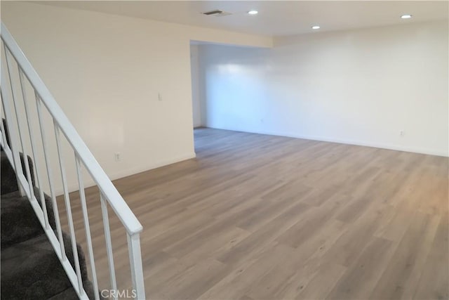 unfurnished room featuring recessed lighting, visible vents, light wood-style flooring, stairway, and baseboards