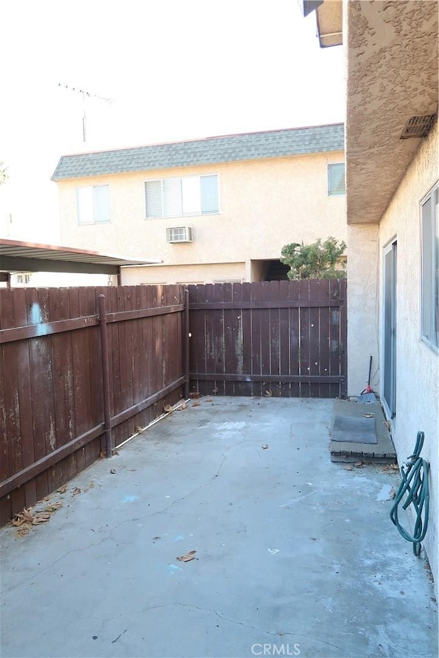 view of patio / terrace with a wall unit AC and fence