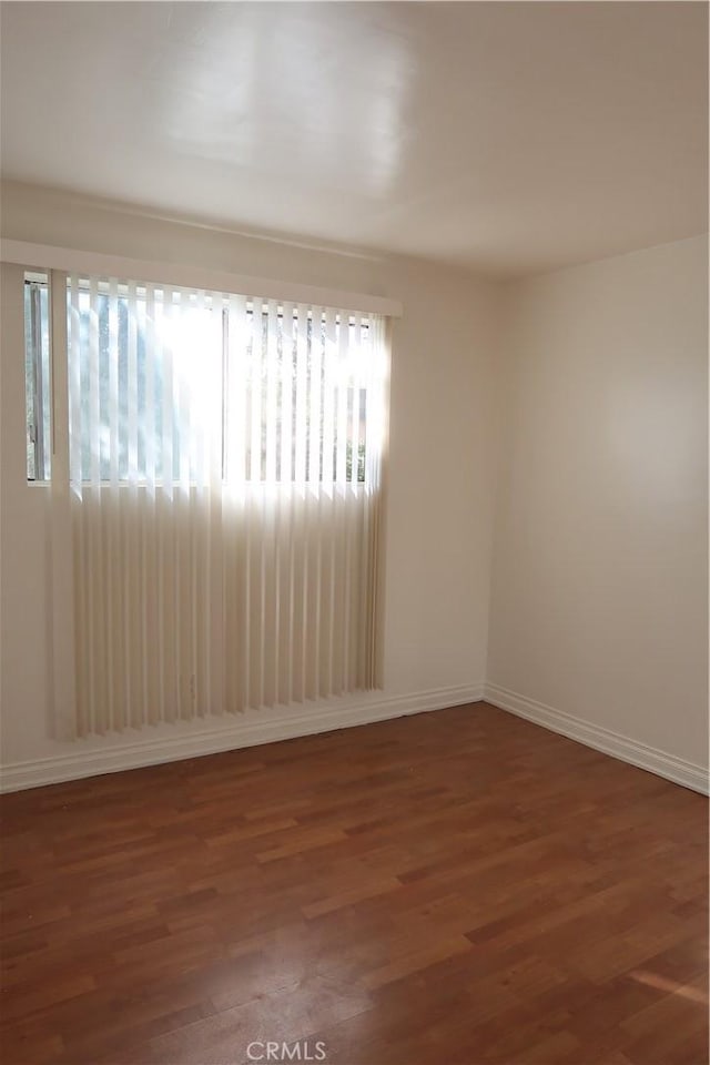 spare room featuring baseboards and wood finished floors