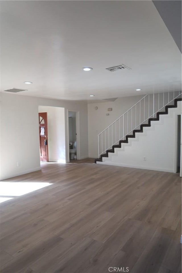 interior space with stairway, wood finished floors, and visible vents