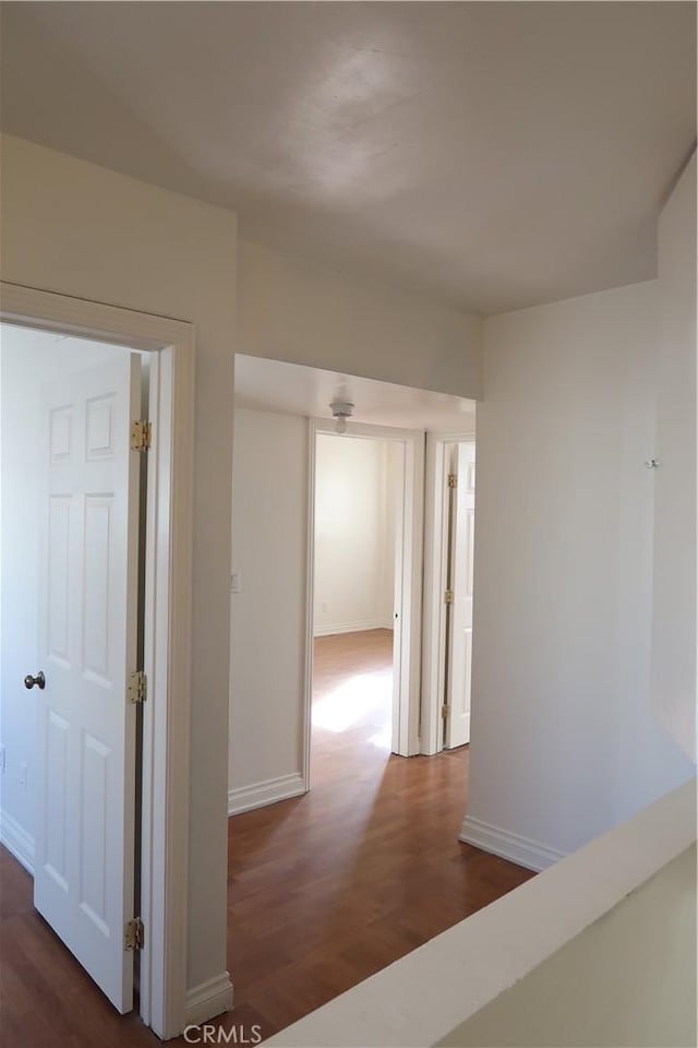 hall with dark wood-style flooring and baseboards