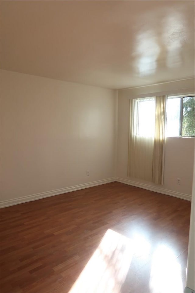 unfurnished room with baseboards and wood finished floors