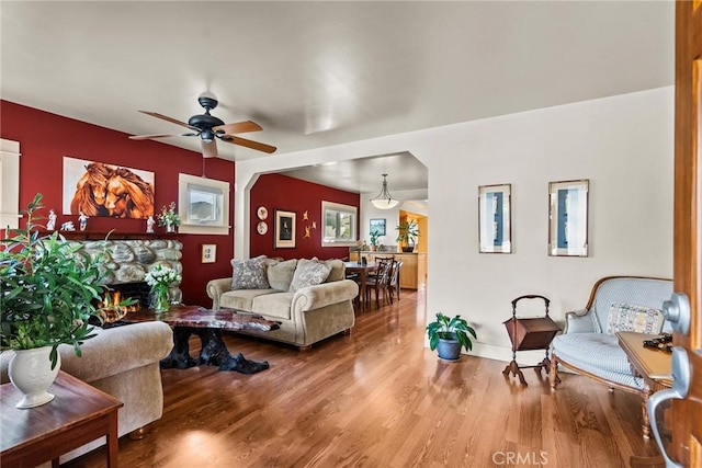 living room with a fireplace, wood finished floors, and a ceiling fan