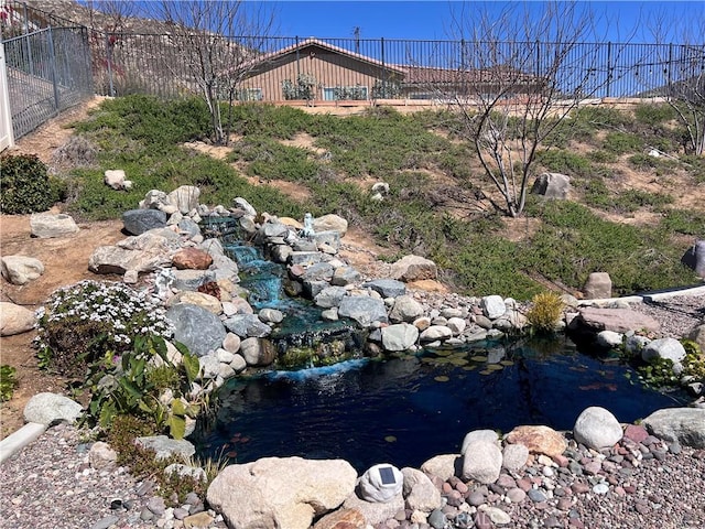 view of yard featuring a small pond and fence