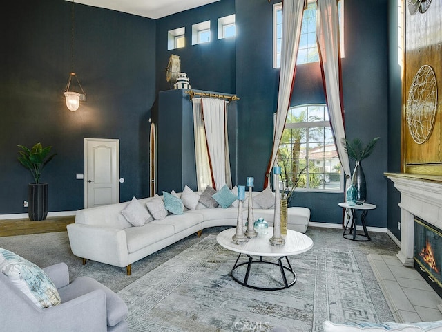 living area with a glass covered fireplace, baseboards, and a high ceiling