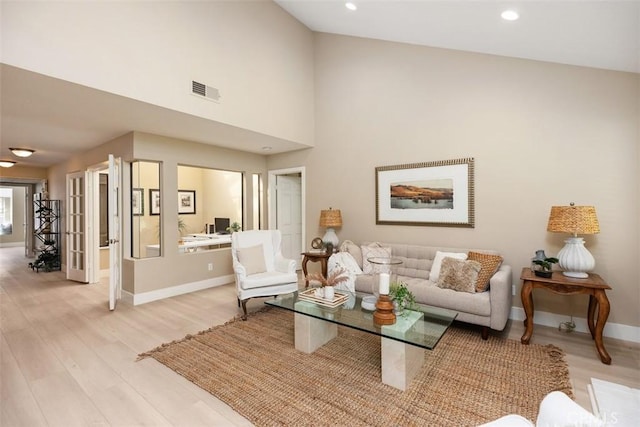 living area with visible vents, baseboards, light wood finished floors, high vaulted ceiling, and recessed lighting