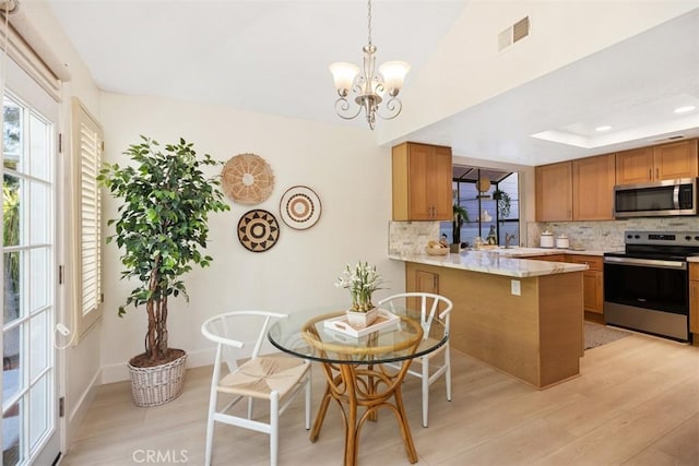 kitchen with visible vents, a tray ceiling, decorative backsplash, brown cabinets, and appliances with stainless steel finishes