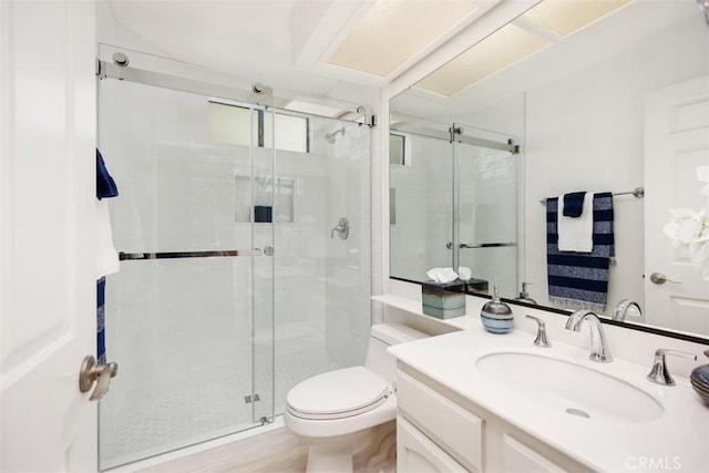 bathroom featuring a shower stall, toilet, and vanity