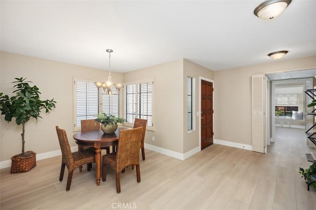 dining space featuring light wood finished floors, a chandelier, and baseboards