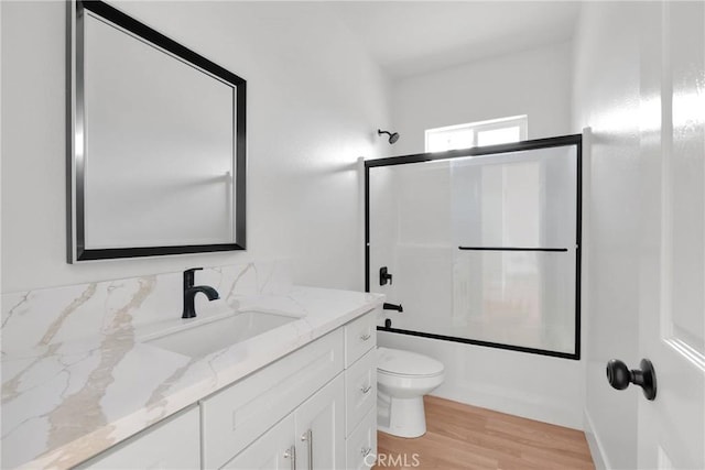 bathroom featuring vanity, combined bath / shower with glass door, wood finished floors, and toilet