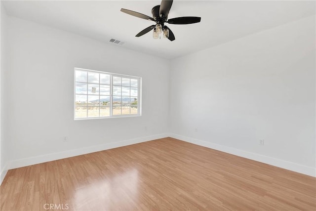 unfurnished room with light wood-style floors, baseboards, visible vents, and a ceiling fan