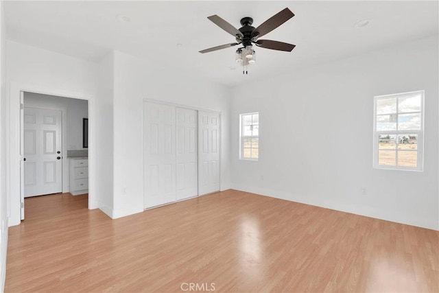 unfurnished bedroom with light wood finished floors, a ceiling fan, and a closet