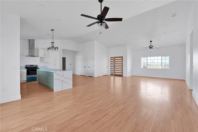 kitchen with light wood-type flooring, wall chimney exhaust hood, a kitchen island, and electric range oven