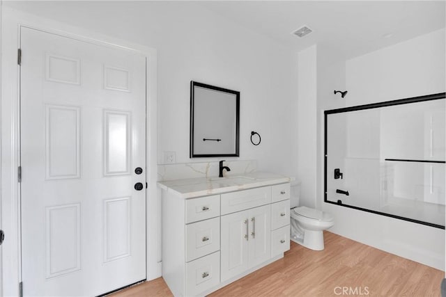 full bath with visible vents, toilet, enclosed tub / shower combo, vanity, and wood finished floors