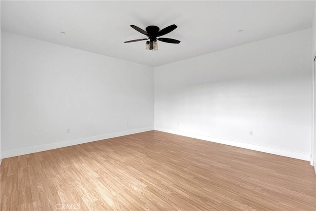 spare room featuring a ceiling fan, light wood-style flooring, and baseboards