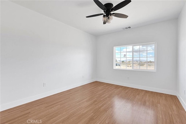 unfurnished room featuring ceiling fan, wood finished floors, visible vents, and baseboards