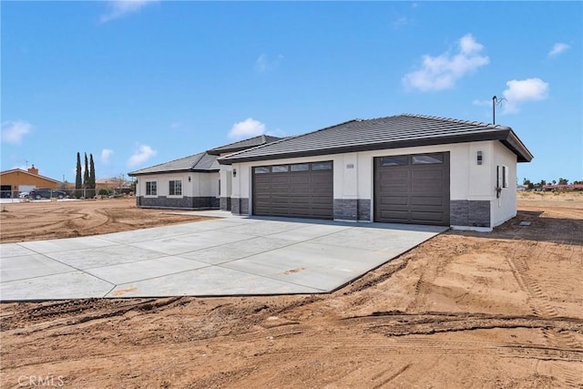 view of front of home with a garage, stone siding, a tiled roof, and concrete driveway